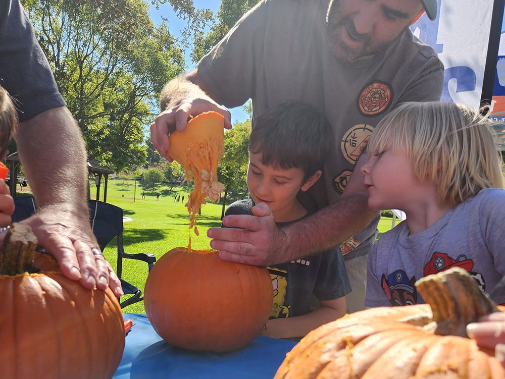 cub scout watching as parent lifts lid off of pumpkin for the first time